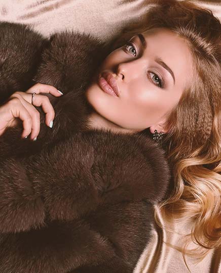 A beautiful woman reclines while wearing a fine fur coat